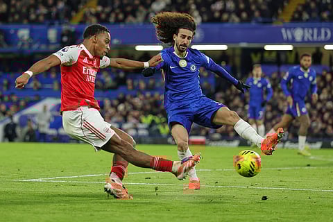 Arsenal's Jurrien Timber, left, kicks the ball ahead of Chelsea's Marc Cucurella during the English Premier League soccer match between Chelsea and Arsenal in London, England.
