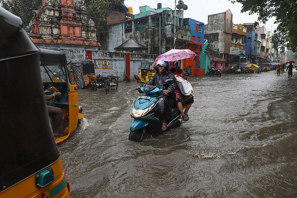 People wade through waterlogged road amid heavy rainfall in the wake of Cyclone Ditwah, in Chennai. - | Photo: PTI/R Senthilkumar