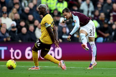 Aston Villa's Matty Cash, right, shoots towards the goal, during the English Premier League soccer match between Aston Villa and Wolverhampton Wanderers, at Villa Park, in Birmingham, England.