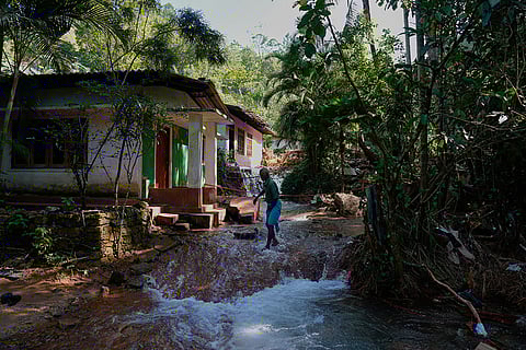 A landslide survivor crosses water at the site of a landslide in Sarasavigama village in Kandy, Sri Lanka.
