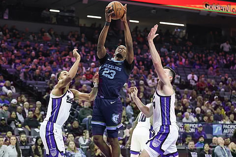 Memphis Grizzlies guard Cedric Coward (23) goes up for a layup with Sacramento Kings forward Keegan Murray, left, and center Drew Eubanks, right, defending during the first half of an NBA basketball game in Sacramento, California. 