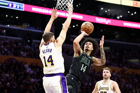 New Orleans Pelicans guard Micah Peavy (14) drives to the basket against Los Angeles Lakers forward Maxi Kleber (14) as guard Luka Doncic, back right, watches during the first half of an NBA basketball game in Los Angeles. 