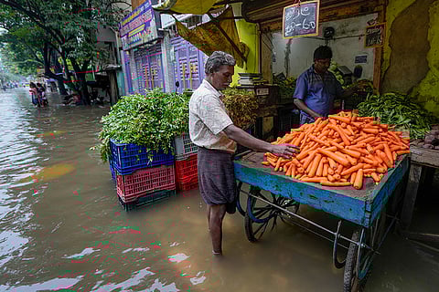 A man shops for vegetable on a waterlogged street following Cyclone Ditwah, in Chennai.
