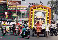 PTI Photo : Coimbatore: Two fans of MG Ramachandran (MGR), former Chief Minister of Tamilnadu, ferry his life-size poster through a street to mark his 25th death anniversary in Coimbatore on Monday.