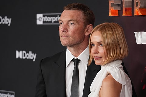 Sam Worthington, left, a cast member in "Avatar: Fire and Ash," arrives with his wife Lara at the premiere of the film at Dolby Theatre in Los Angeles. 