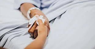 A patient holding a childs hand