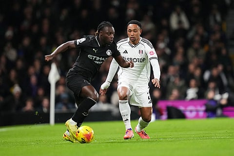 Manchester City's Jeremy Doku, left, fights for the ball with Fulham's Kenny Tete during the English Premier League soccer match between Fulham and Manchester City in London.