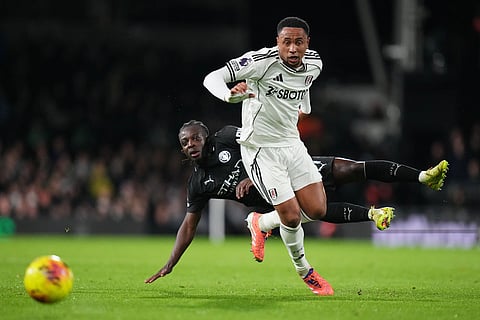 Fulham's Kenny Tete, right, fights for the ball with Manchester City's Jeremy Doku during the English Premier League soccer match between Fulham and Manchester City in London.