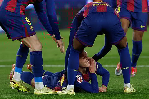 Barcelona's Dani Olmo reacts in pain in his arm after scoring his side's second goal during a Spanish La Liga soccer match between Barcelona and Atletico de Madrid, in Barcelona, Spain.