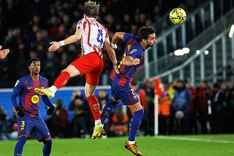 Barcelona's Ferran Torres jumps for the ball against Atletico Madrid's Conor Gallagher during a Spanish La Liga soccer match between Barcelona and Atletico de Madrid, in Barcelona, Spain.