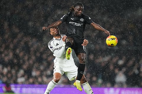 Manchester City's Jeremy Doku, right, goes up against Fulham's Kenny Tete during the English Premier League soccer match between Fulham and Manchester City in London.