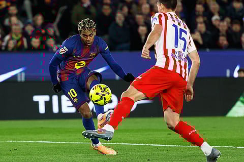 Barcelona's Lamine Yamal fights for the ball against Atletico Madrid's Clement Lenglet during a Spanish La Liga soccer match between Barcelona and Atletico de Madrid, in Barcelona, Spain.
