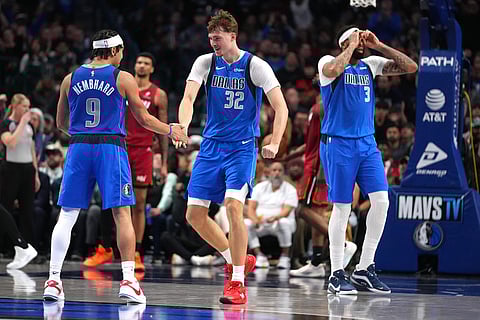 Dallas Mavericks guard Ryan Nembhard (9), forward Cooper Flagg (32) and forward Anthony Davis (3) react after a basket against the Miami Heat during the second half of an NBA basketball game in Dallas. 