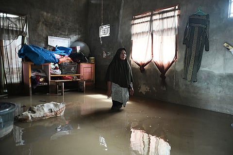 A woman stands inside her flooded house in Pidie Jaya, Aceh province, Indonesia.