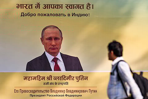A man walks past a hoarding featuring Russian President Vladimir Putin ahead of Putin's visit to India, in New Delhi.
