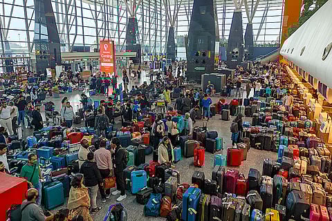 Stranded passengers search for their luggage near a counter after IndiGo cancelled more than 400 flights, at the Kempegowda International Airport, in Bengaluru, Karnataka.