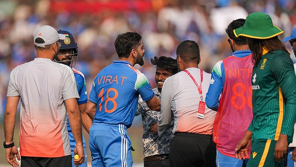 India's Virat Kohli, center, being greeted by a pitch invader between overs during the second ODI cricket match of a series between India and South Africa, at Shaheed Veer Narayan Singh International Stadium, in Raipur, Chhattisgarh.  - | Photo: PTI/Kunal Patil
