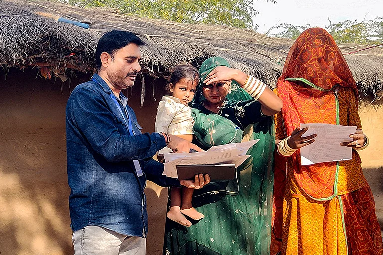 A booth level officer (BLO) assists voters in filling out enumeration forms for the special intensive revision (SIR) of electoral rolls, in Bikaner, Rajasthan. - | Photo: PTI