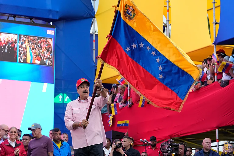 President Nicolas Maduro waves a Venezuelan flag during a swearing-in event for government-organized community committees at the presidential palace in Caracas, Venezuela, Monday, Dec. 1, 2025. - Ariana Cubillos