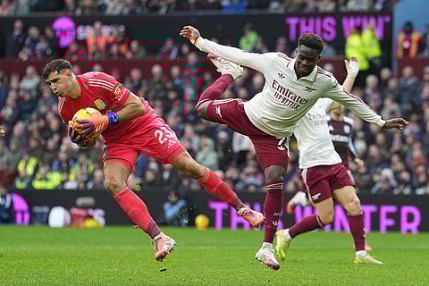 Aston Villa's goalkeeper Emiliano Martinez, left, makes a save ahead of Arsenal's Bukayo Saka during the English Premier League soccer match between Aston Villa and Arsenal in Birmingham, England.