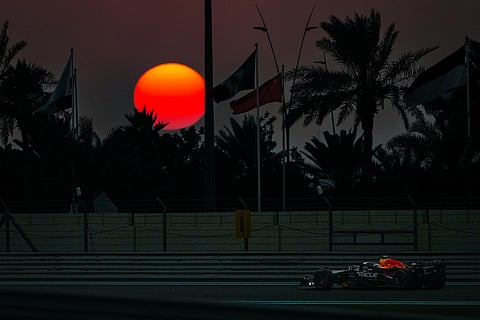 Red Bull driver Max Verstappen of the Netherlands steers his car during the Formula One Abu Dhabi Grand Prix at Yas Marina Circuit in Abu Dhabi, United Arab Emirates as the sun sets behind the track.