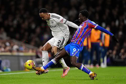 Fulham's Kenny Tete, left, and Crystal Palace's Eddie Nketiah battle for the ball during the English Premier League soccer match between Fulham and Crystal Palace, in London.