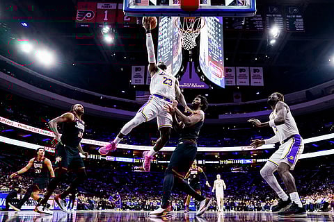 Los Angeles Lakers' LeBron James, center left, goes up for the shot against Philadelphia 76ers' Joel Embiid, center right, during the second half of an NBA basketball game in Philadelphia.