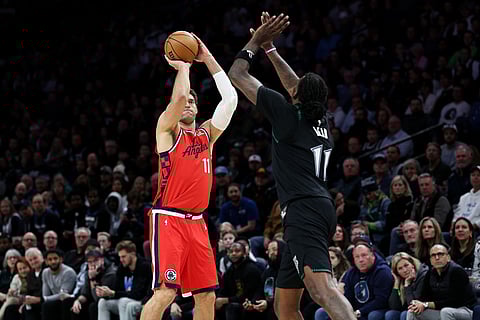 Los Angeles Clippers center Brook Lopez, left, shoots the ball as Minnesota Timberwolves center Naz Reid (11) defends during the second half of an NBA basketball game in Minneapolis.