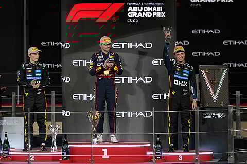 Race winner Red Bull driver Max Verstappen of the Netherlands, center, poses on the podium with second placed McLaren driver Oscar Piastri of Australia, left, and third placed McLaren driver Lando Norris of Britain after the Formula One Abu Dhabi Grand Prix at the Yas Marina Circuit in Abu Dhabi, UAE.