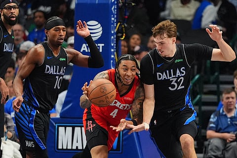 Houston Rockets guard JD Davison (4) tries to move the ball against Dallas Mavericks forward Cooper Flagg (32) as Brandon Williams, left, and Anthony Davis look on during the second half of an NBA basketball game in Dallas.