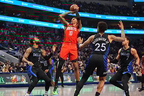 Houston Rockets forward Jabari Smith Jr. (10) goes up to shoot against Dallas Mavericks defenders D'Angelo Russell (5), P.J. Washington (25) and Dwight Powell (7) during the first half of an NBA basketball game in Dallas.