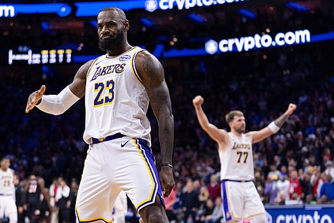 Los Angeles Lakers' LeBron James, left, reacts to his three point shot with Luka Doncic, right, celebrating during the second half of an NBA basketball game against the Philadelphia 76ers in Philadelphia.