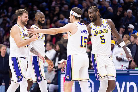 Los Angeles Lakers' Luka Doncic, left, celebrates with LeBron James, second from left, Austin Reaves (15) and Deandre Ayton (5) during the second half of an NBA basketball game against the Philadelphia 76ers in Philadelphia. 