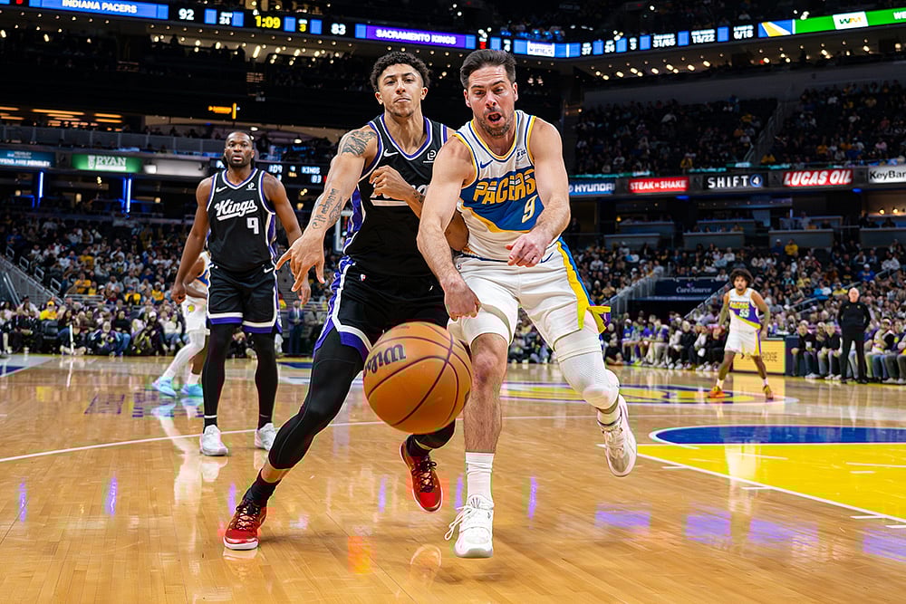 Sacramento Kings guard Nique Clifford, left, and Indiana Pacers guard T.J. McConnell (9) battle for the ball during the second half of an NBA basketball game in Indianapolis. - | Photo: AP/Doug McSchooler