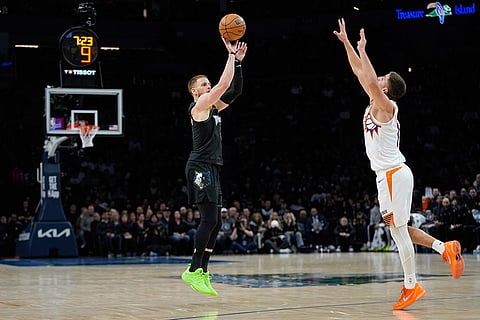 Minnesota Timberwolves guard Donte DiVincenzo, left, shoots over Phoenix Suns guard Collin Gillespie during the first half of an NBA basketball game in Minneapolis. 