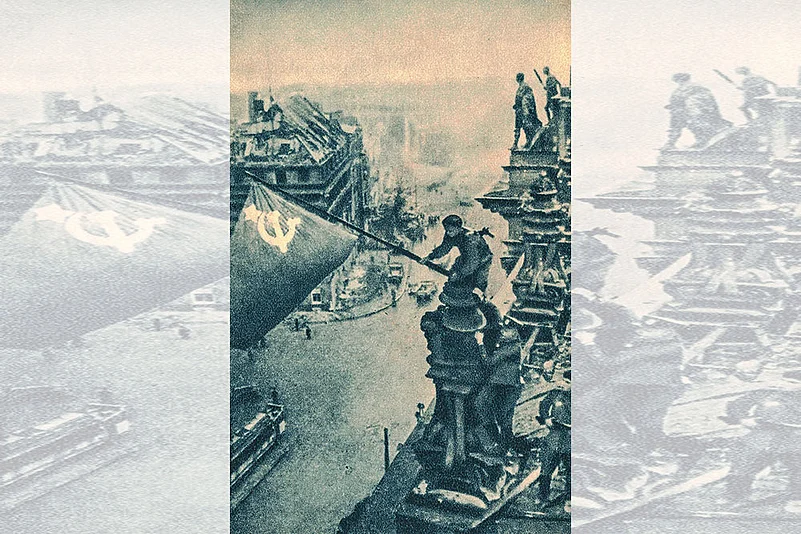 Two Soviet soldiers plant a Soviet flag on top of the Reichstag building.