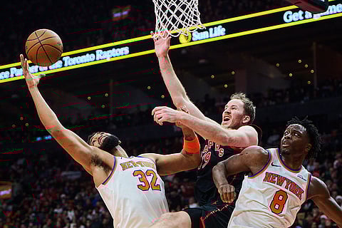 Toronto Raptors' Jakob Poeltl (19) is stopped at the net by New York Knicks' Karl-Anthony Towns (32) and New York Knicks' OG Anunoby (8) during the first half of an NBA Cup basketball game in Toronto.