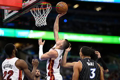 Miami Heat guard Tyler Herro (14) puts up a shot as forward Andrew Wiggins (22) and Orlando Magic guard Desmond Bane (3) look on during the first half of an NBA Cup basketball game in Orlando, Florida. 