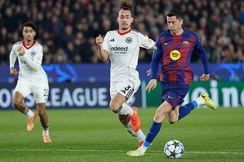 Barcelona's Robert Lewandowski, right, is challenged by Frankfurt's Arthur Theate during the Champions League opening phase soccer match between Barcelona and Eintracht Frankfurt in Barcelona, Spain.
