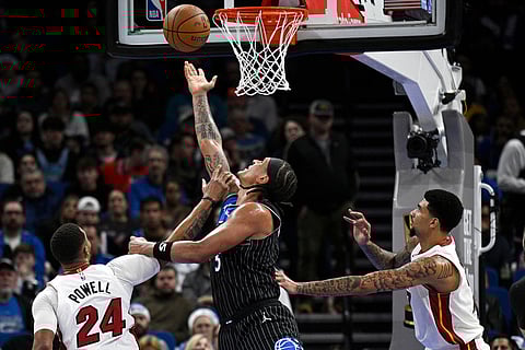 Orlando Magic forward Paolo Banchero (5) goes up to shoot between Miami Heat guard Norman Powell (24) and center Kel'El Ware, right, during the first half of an NBA Cup basketball game in Orlando, Florida. 