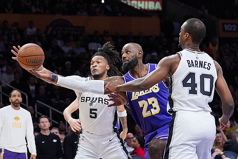 Los Angeles Lakers forward Lebron James (23) goes after a loose ball against San Antonio Spurs forward Harrison Barnes (40) and guard Stephon Castle (5) during the first half of an NBA Cup basketball game in Los Angeles.