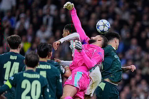 Manchester City's goalkeeper Gianluigi Donnarumma, center, fights for a high ball with Real Madrid's Jude Bellingham, left, during a Champions League opening phase soccer match between Real Madrid and Manchester City, in Madrid, Spain.
