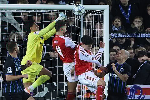 Brugge's goalkeeper Tristan van den Heuvel, second left, goes up for a save against Arsenal's Ben White, center, during the Champions League opening phase soccer match between Club Brugge and Arsenal in Bruges, Belgium.