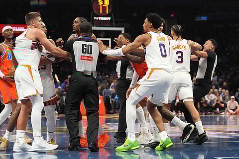 Officials try to keep the Oklahoma City Thunder players away from the Phoenix Suns as a scuffle breaks out during the second half of an NBA Cup basketball game in Oklahoma City.