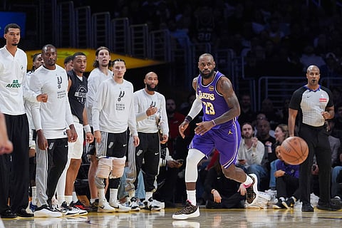Los Angeles Lakers forward Lebron James (23) makes his way down the court past the bench of the San Antonio Spurs during the first half of an NBA Cup basketball game in Los Angeles.