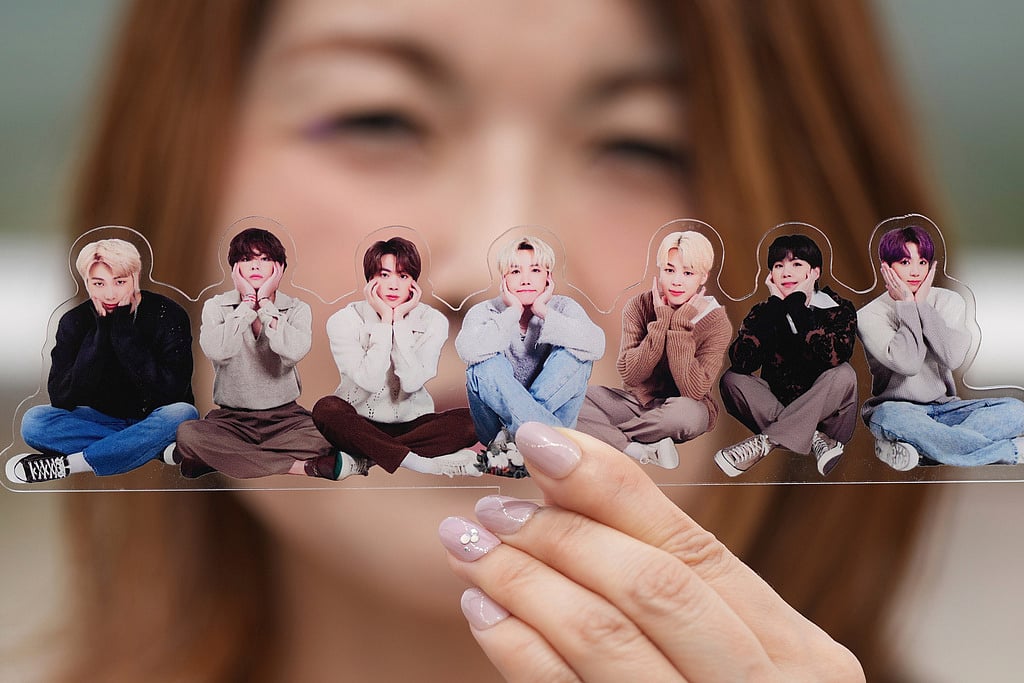 A fan poses with a group photo of BTS