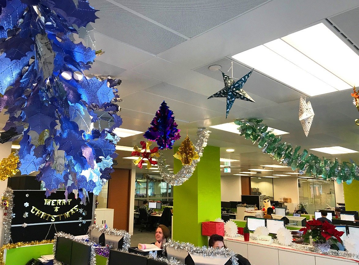 Office decorated for Christmas with blue foliage, tinsel, and a large hanging star ornament.