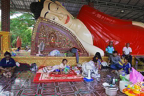 People sit next to a Buddha statue as they take refuge in Koak Kroal's Buddhist pagoda, Siem Reap province, Cambodia after fleeing from home following a fighting between Thailand and Cambodia over territorial claims. 