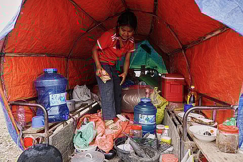 An evacuated young girl collects food in a tent as she takes refuge in Batthkoa primary school in Oddar Meanchey province, Cambodia after fleeing home following fighting between Thailand and Cambodia over territorial claims. 