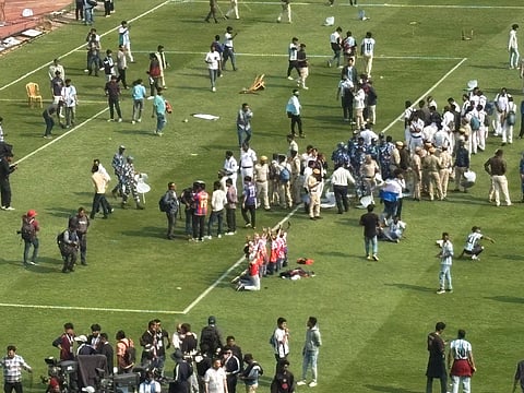 Fans protesting in the middle of the pitch with police and RAF personnel surrounding them.